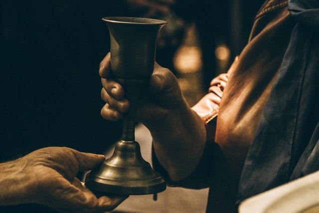 A close-up of the chalice at communion being offered to a communicant.
